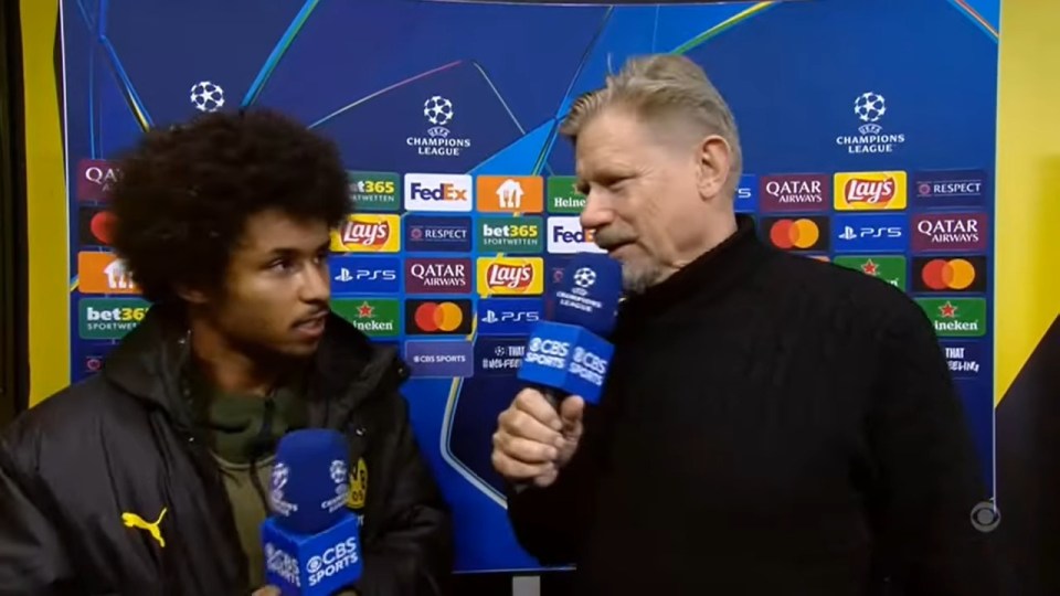 a man holding a microphone in front of a wall that says champions league