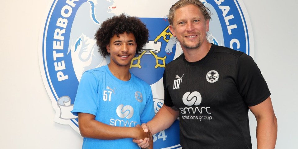 two men shaking hands in front of a peterborough fc logo