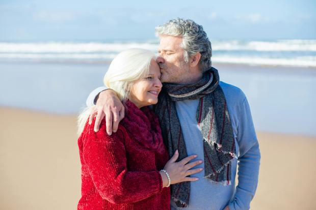 a man kisses a woman on the forehead on the beach