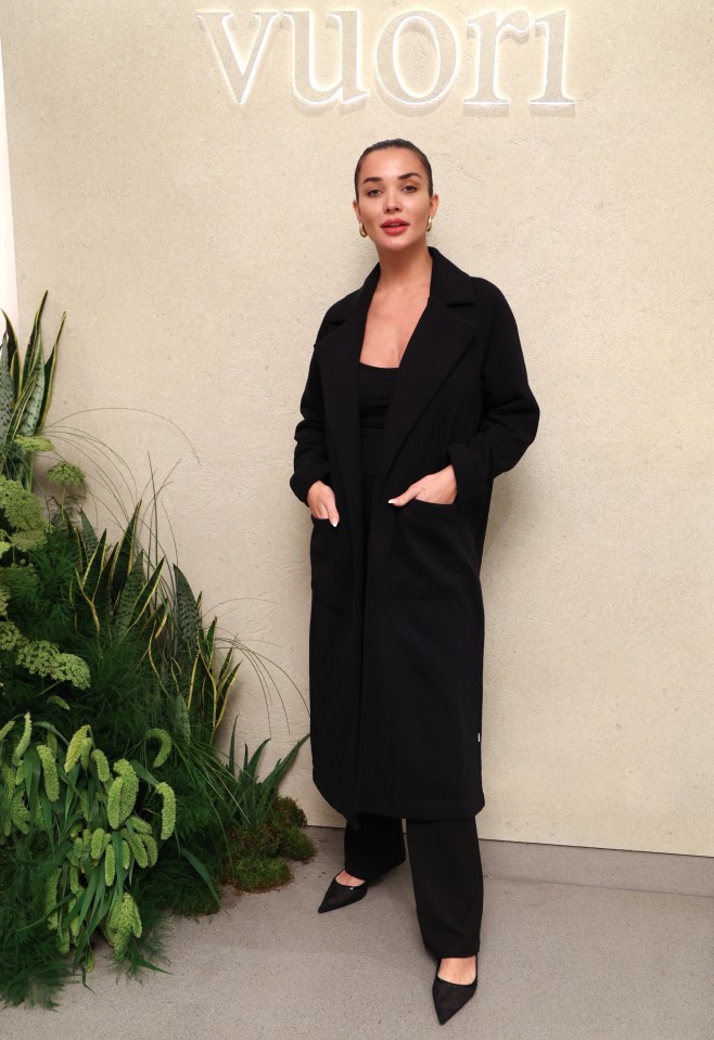 a woman in a black coat stands in front of a sign that says vuori