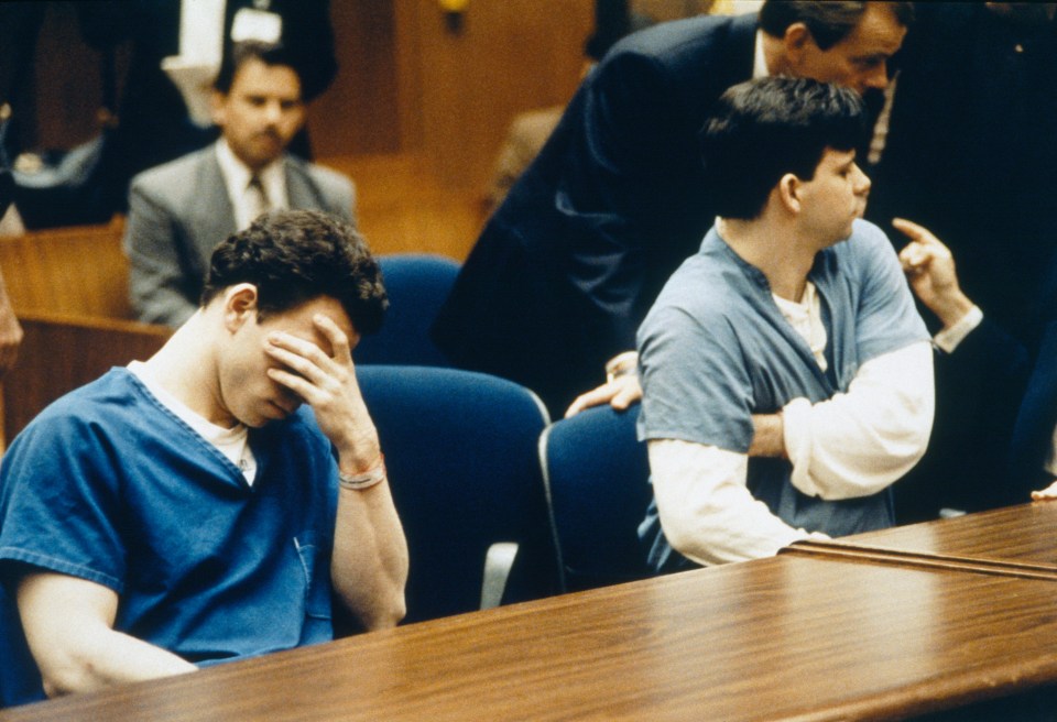 two men in suits and ties sit in a courtroom