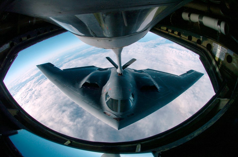 a fighter jet is being refueled by a tanker in the sky