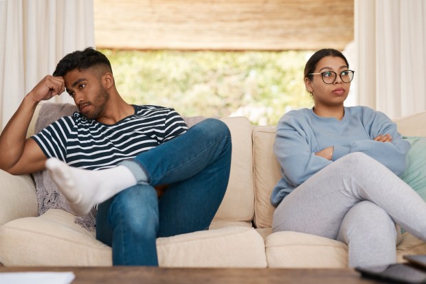 a man and a woman sit on a couch with their arms crossed