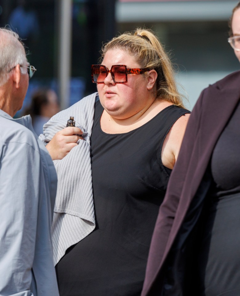 a woman wearing sunglasses and a black tank top talks to a man