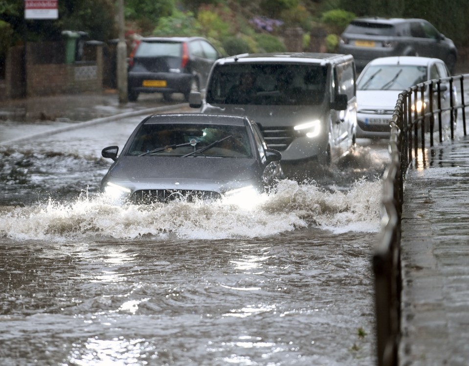 cars are driving through a flooded street with a sign that says ' ambulance ' on it