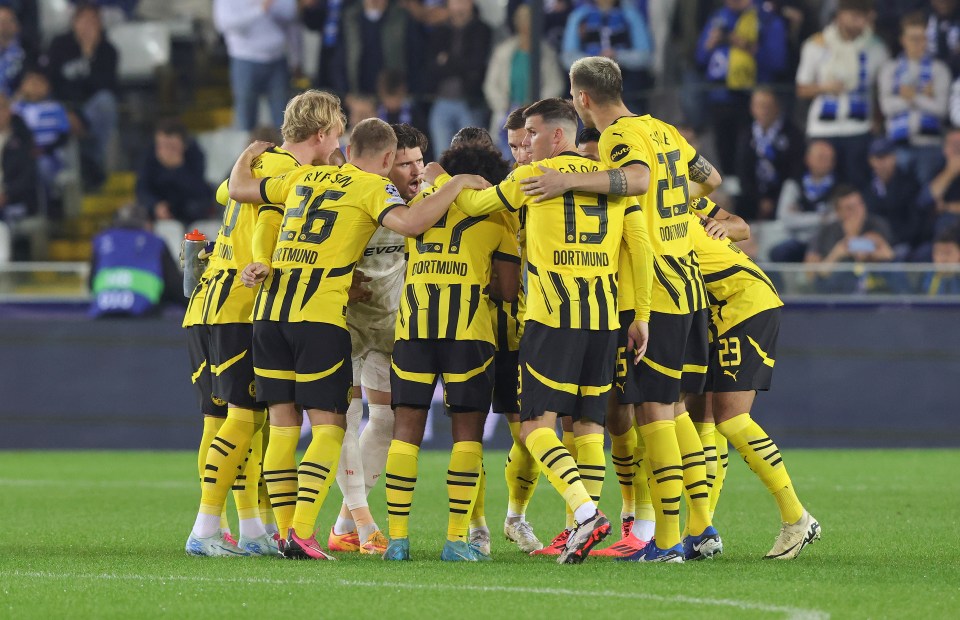 a group of soccer players are huddled together with one wearing a jersey that says dortmund