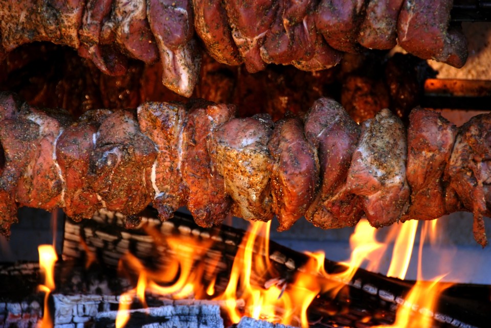 a large piece of meat is hanging over a fire