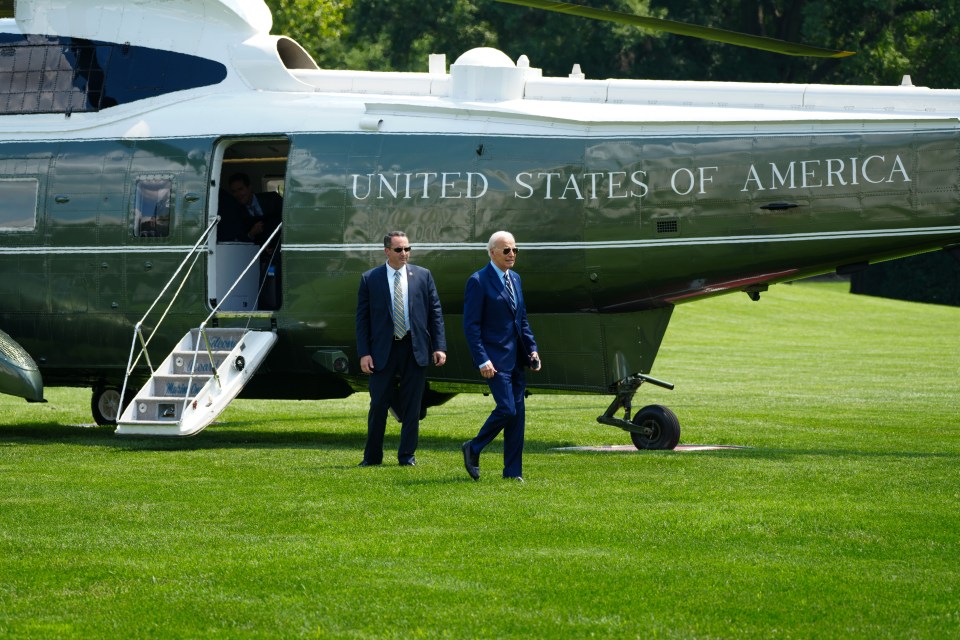 two men walk in front of a united states of america helicopter