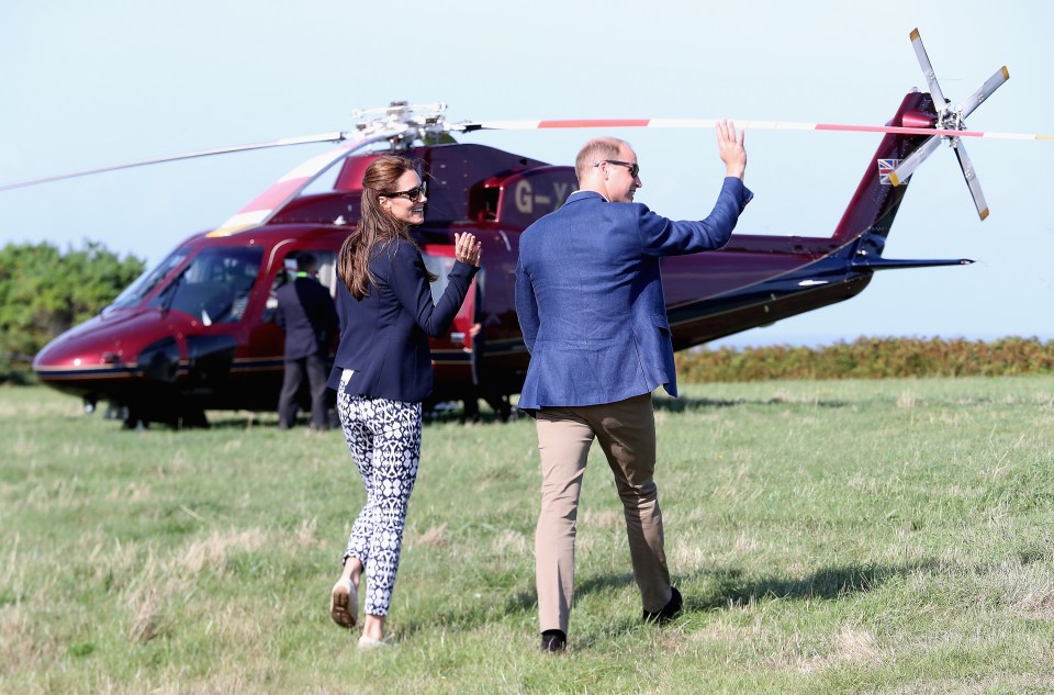 a man and woman standing in front of a helicopter with g-vj on the tail