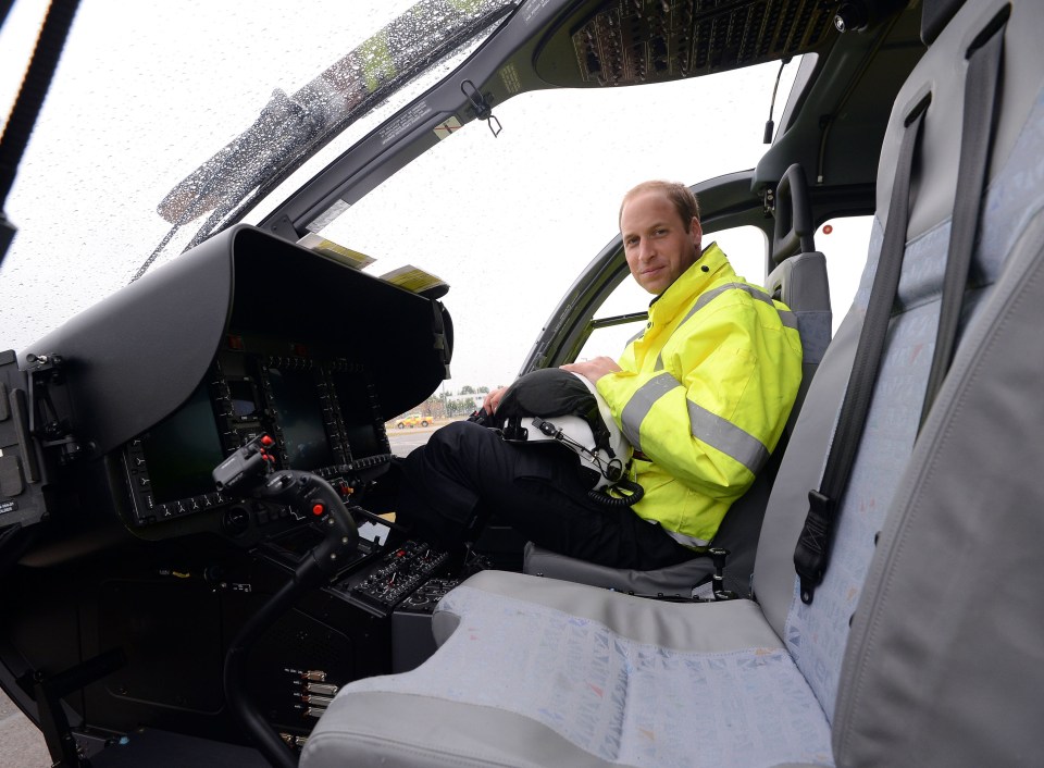 a man in a yellow jacket sits in the cockpit of a helicopter