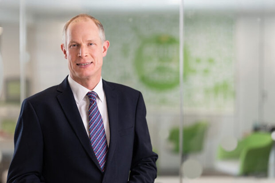 a man in a suit and tie stands in front of a green wall