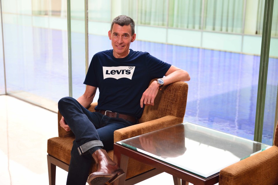 a man wearing a blue levi 's shirt sits in a chair