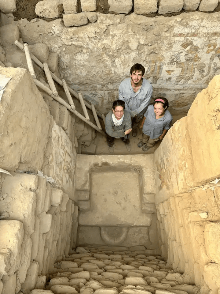 a group of people standing in a cave with a ladder