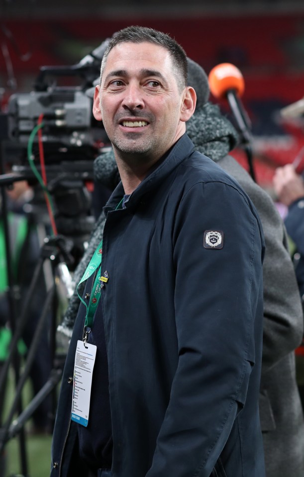 a man wearing a blue jacket with a logo on the sleeve