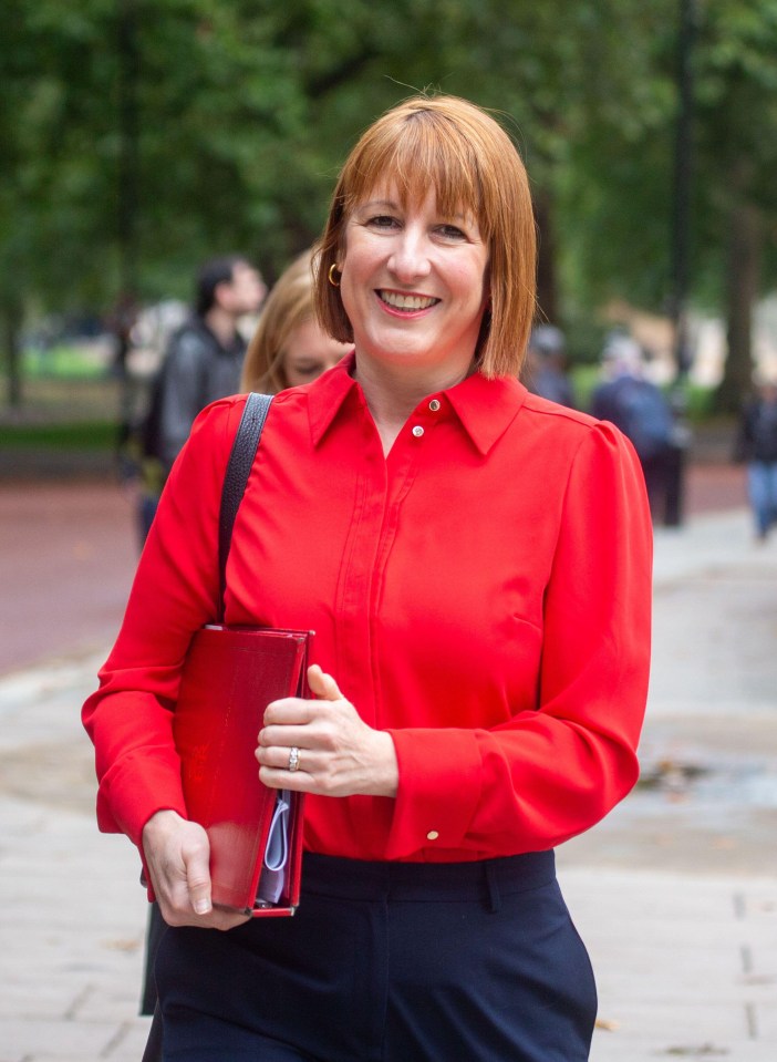 a woman in a red shirt is smiling and holding a red folder