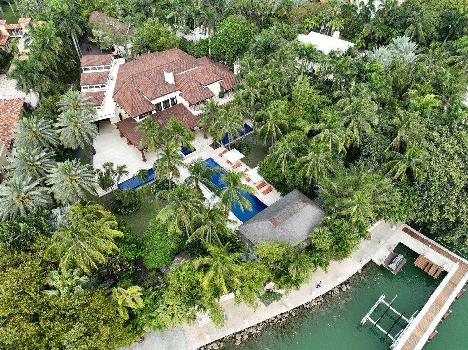 an aerial view of a large house surrounded by palm trees