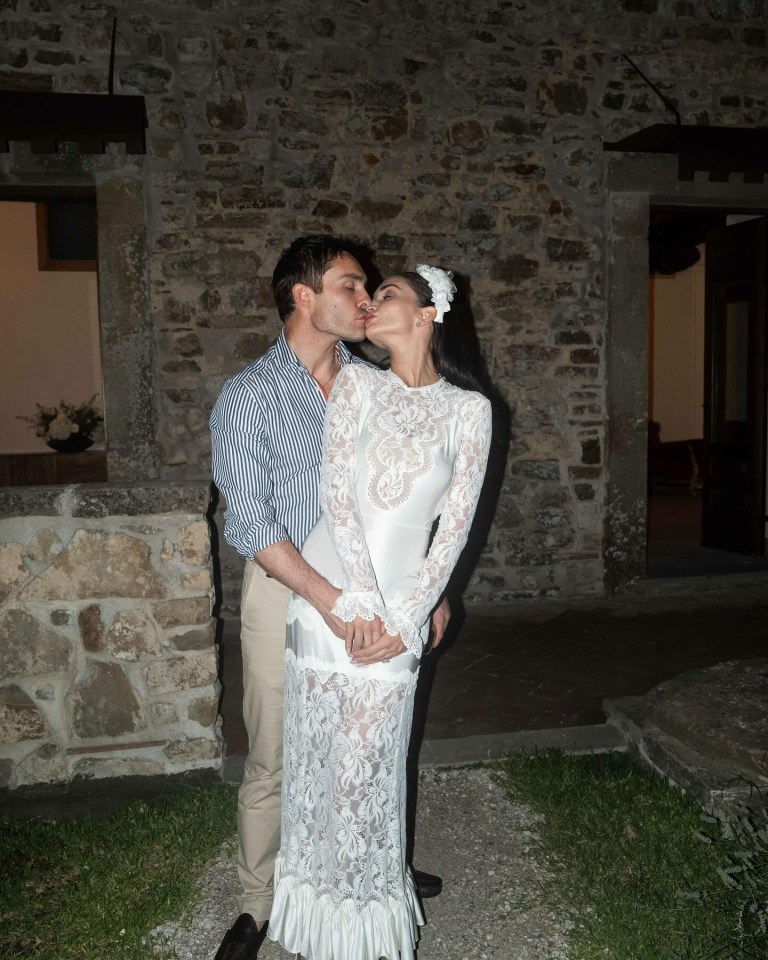 a man kisses a woman on the cheek in front of a stone wall