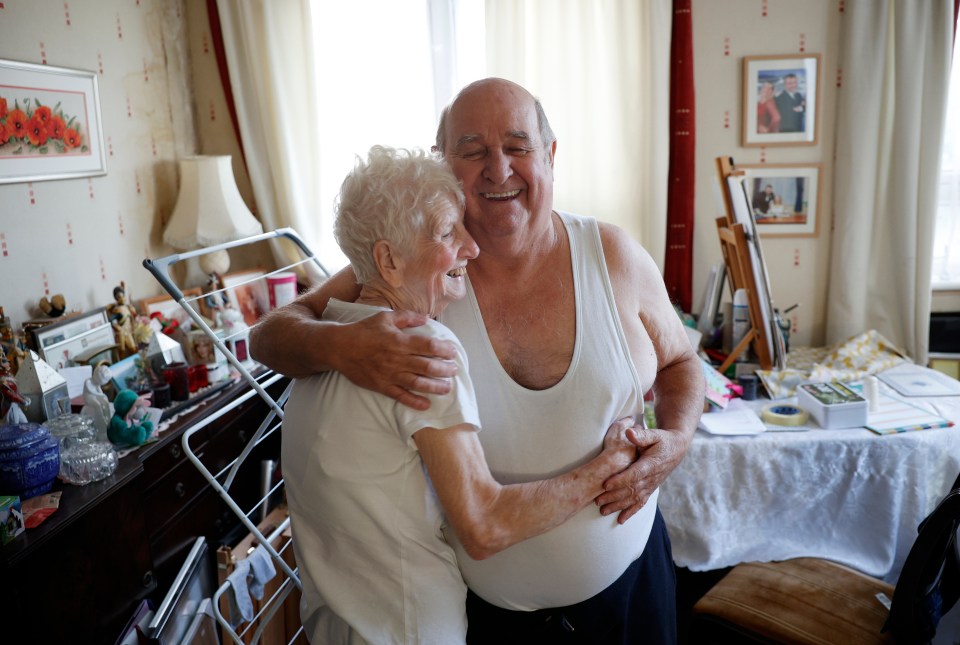 a man in a white tank top is hugging an older woman