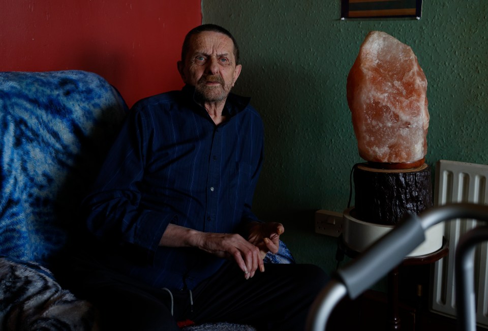 an elderly man sits in a chair next to a walker