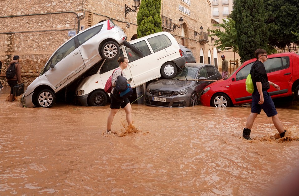 Locals walking past cars piled high in Valencia