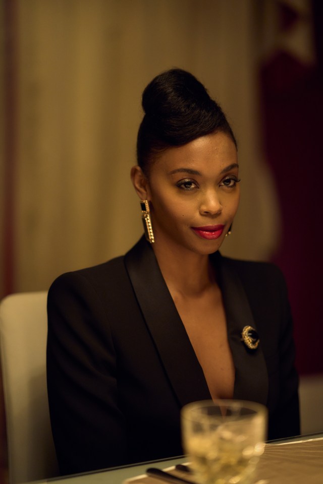 a woman wearing a black jacket and gold earrings is sitting at a table