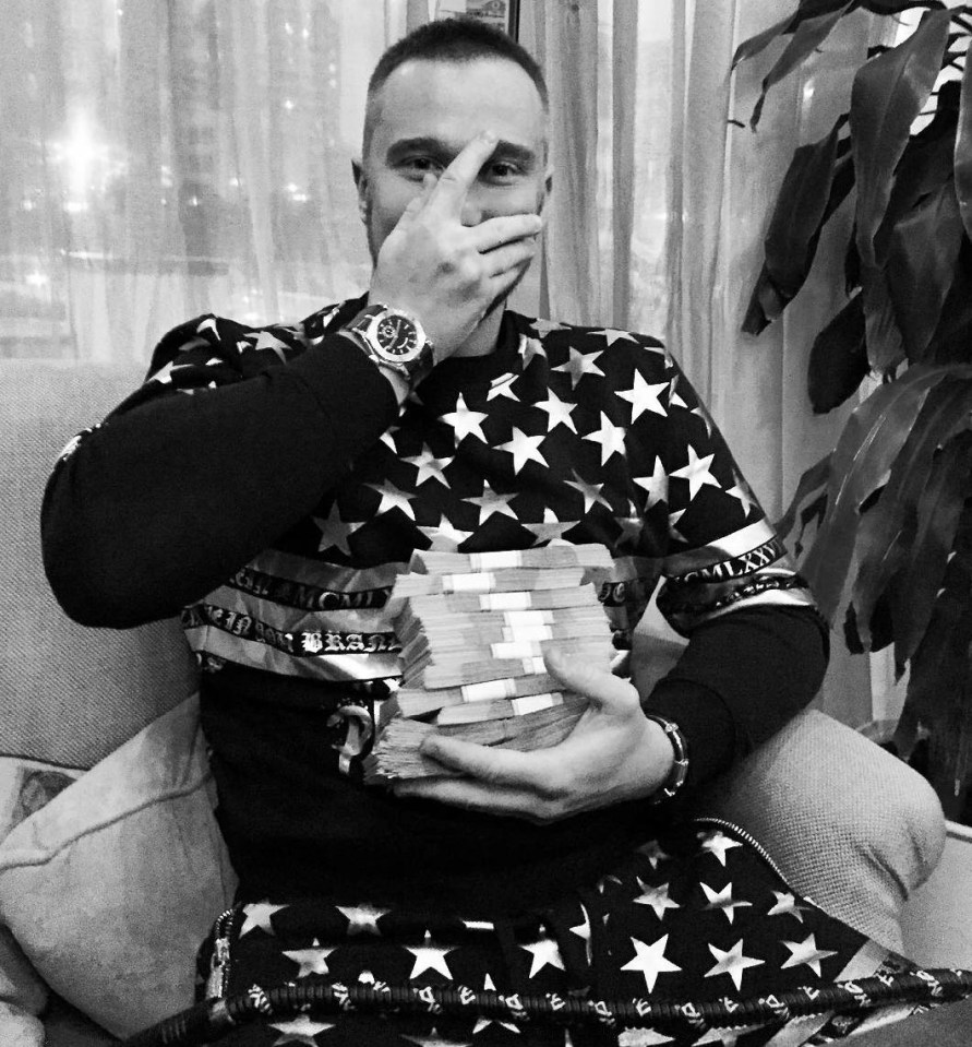 a man in an american flag shirt holds a stack of money