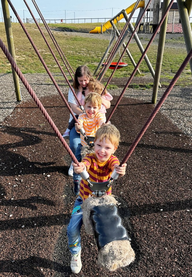 a group of children are playing on a swing set