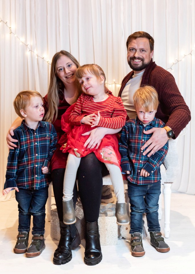 a family posing for a picture with one child wearing a red dress