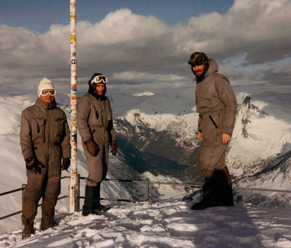 three people standing in front of a pole with the letter g on it