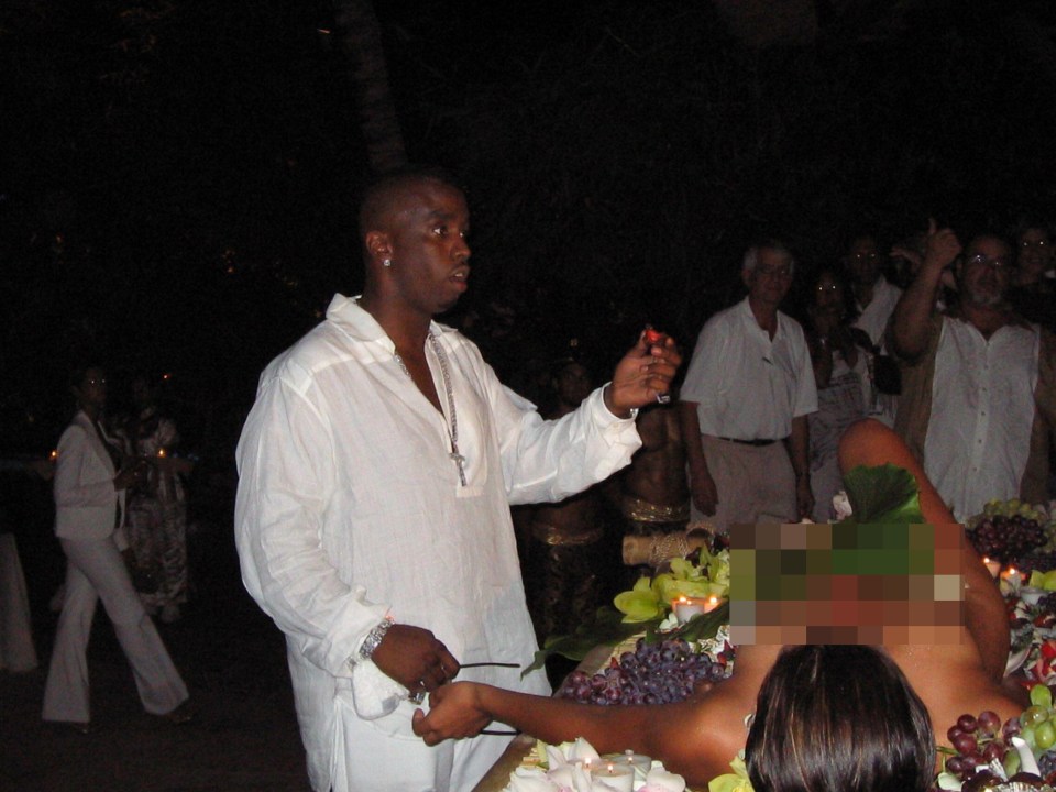 Combs’ standing next to a naked woman laying on a table covered in food at his Fabulous 50 Dinner Party in 2004