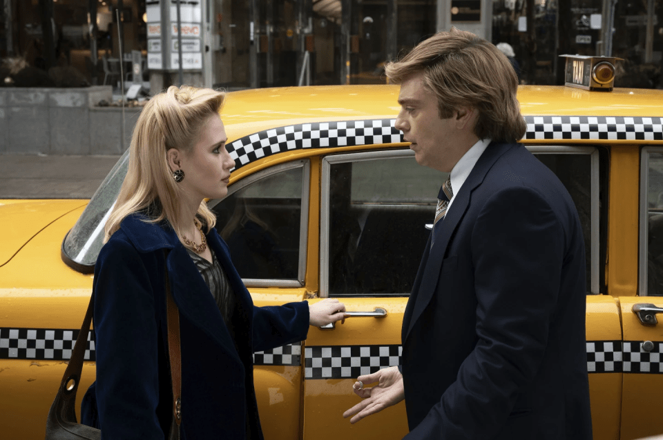 a man and a woman are standing in front of a checkered taxi