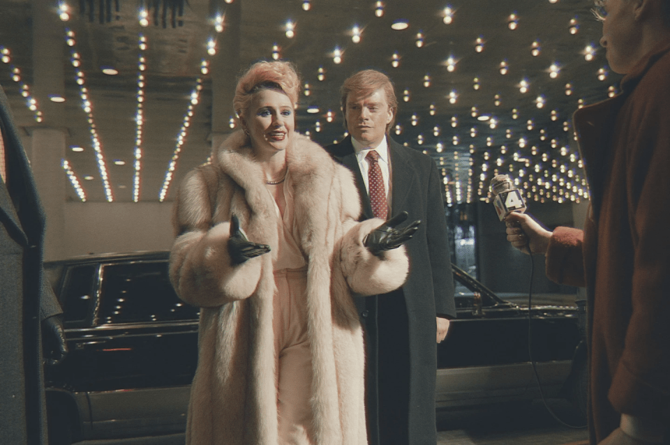 a woman in a fur coat stands next to a man in a suit