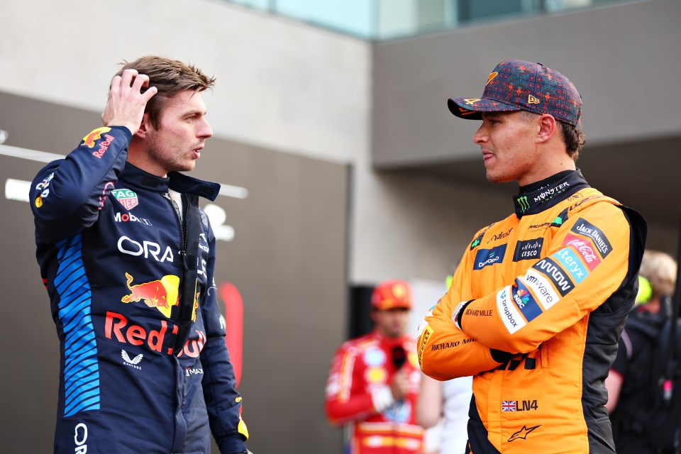 a man wearing a red bull jacket talks to another man