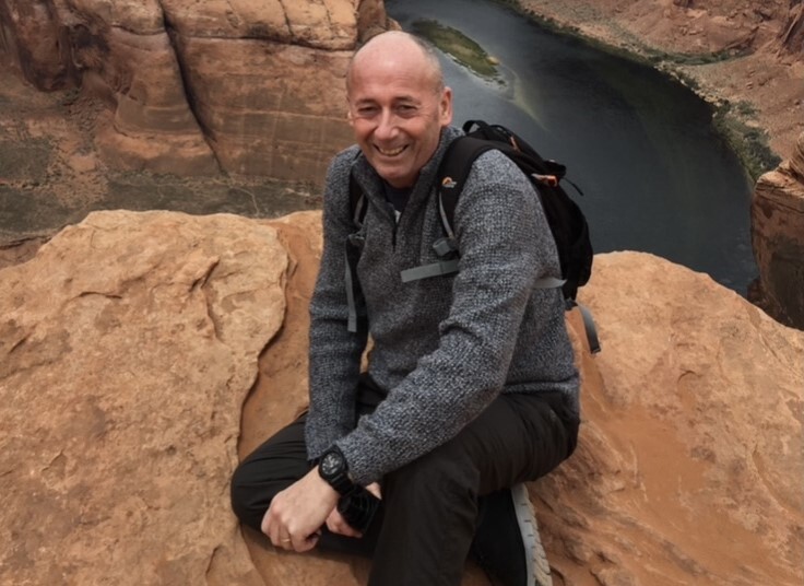 a man with a backpack sits on a rock near a river