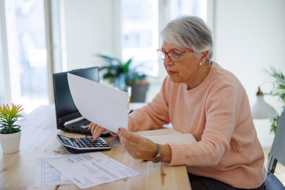 an older woman is using a calculator while holding a piece of paper