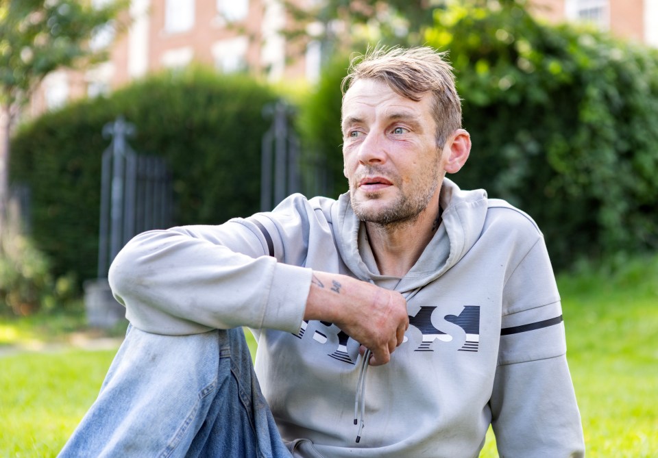 a man wearing a grey sweatshirt with the letter s on it