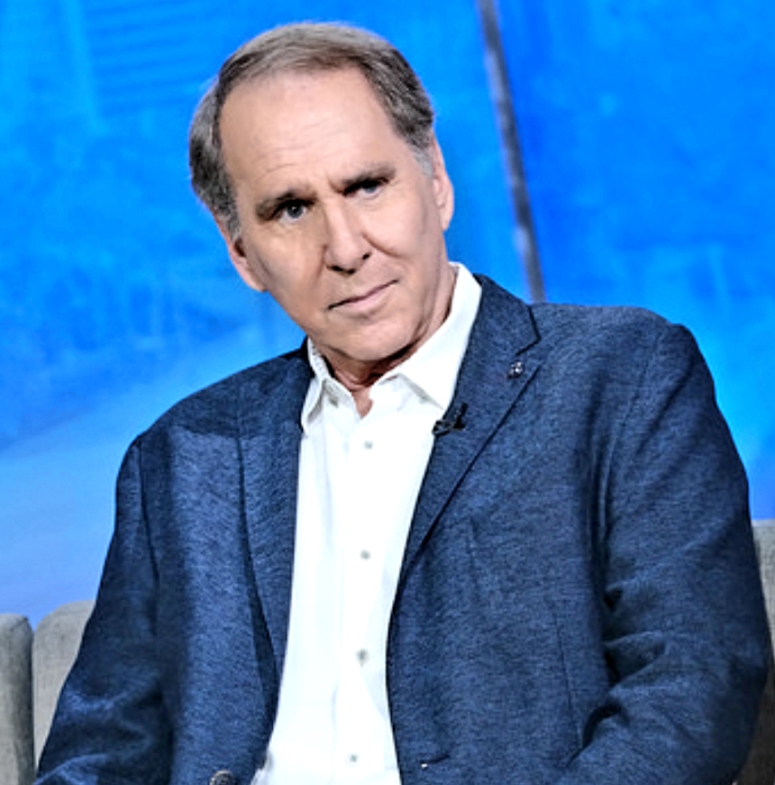 a man in a blue jacket and white shirt is sitting in front of a blue background