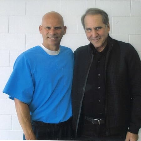 two men are standing next to each other in front of a white brick wall .