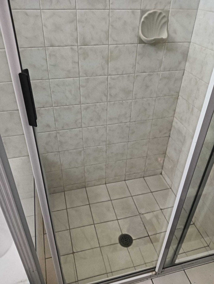 a shower stall with white tiles and a black handle