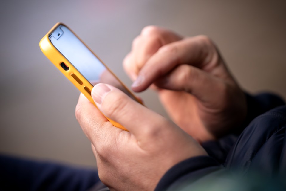 a person is holding a yellow cell phone in their hands