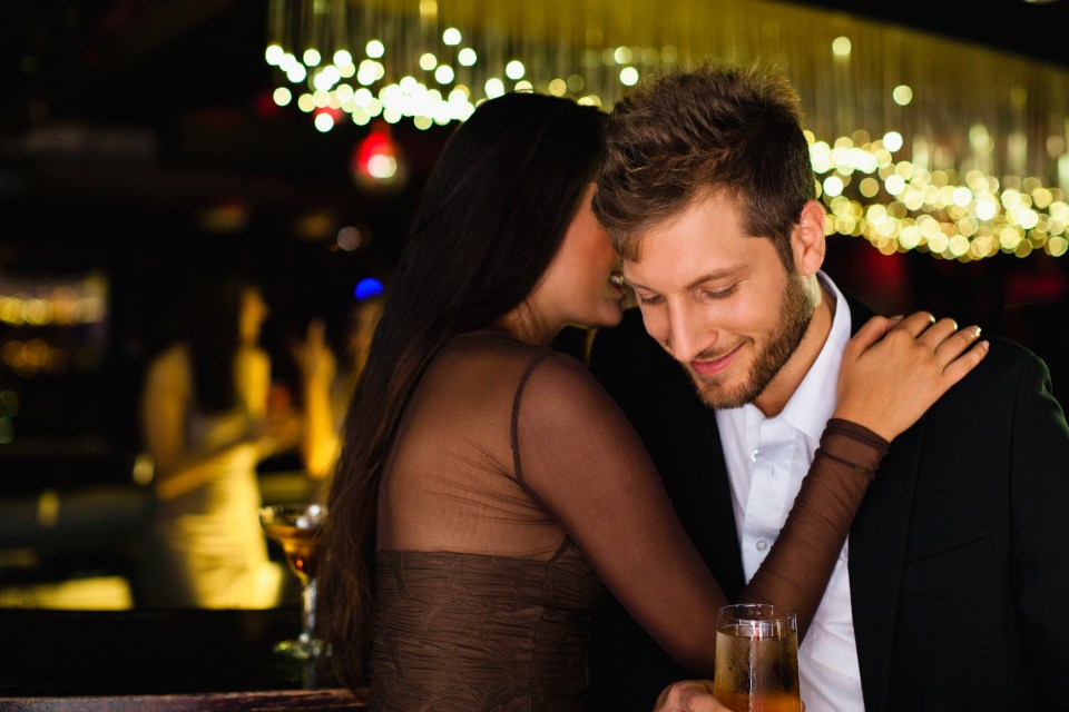 a woman kisses a man on the cheek while holding a glass of wine