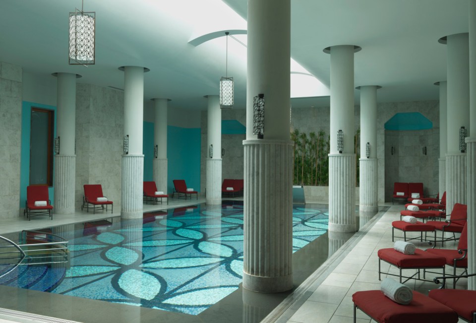 a large indoor swimming pool with columns and chairs