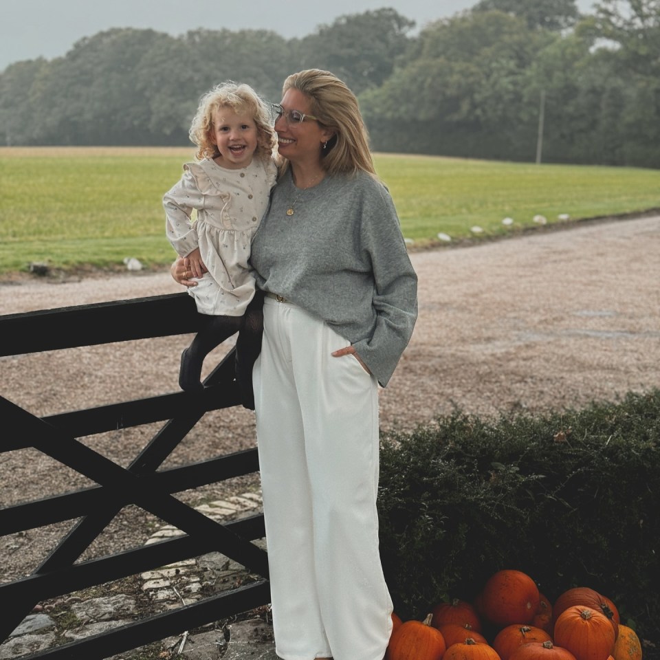 a woman and a little girl are standing next to pumpkins