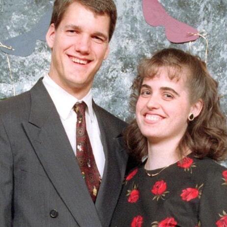 a man in a suit and tie is standing next to a woman in a floral dress .