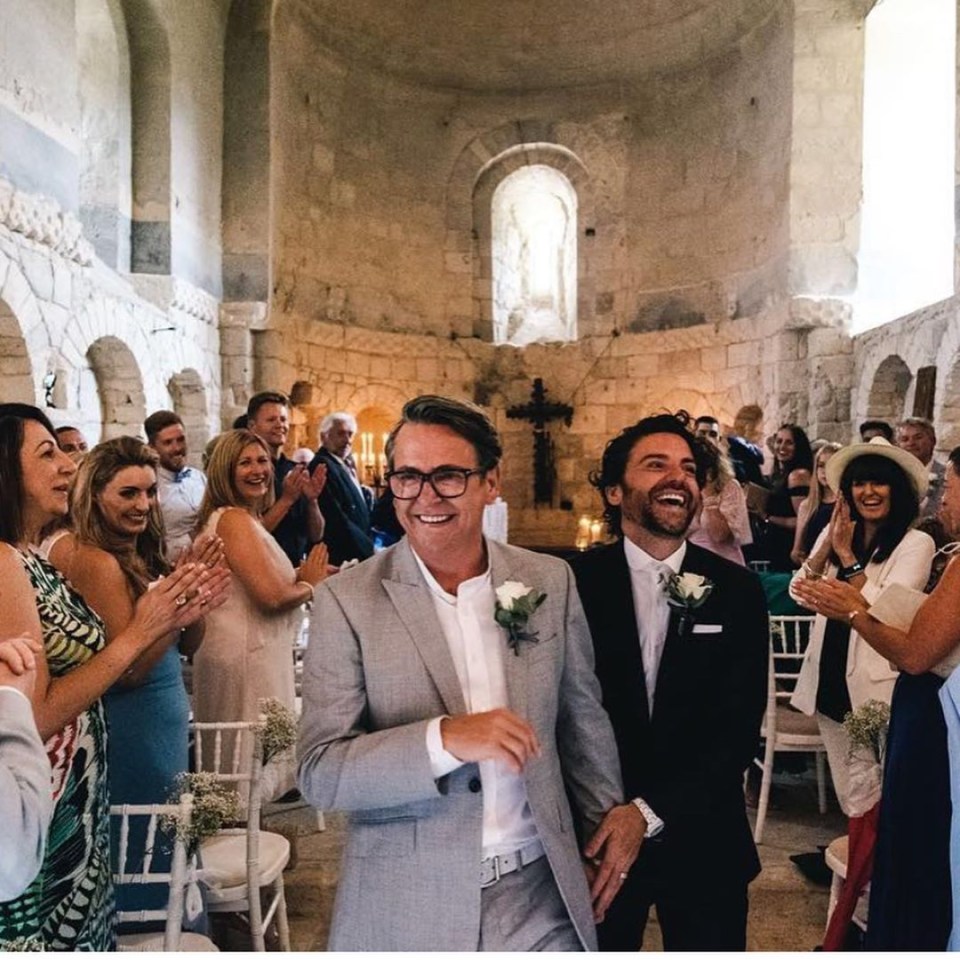 two men in suits are walking down the aisle at a wedding