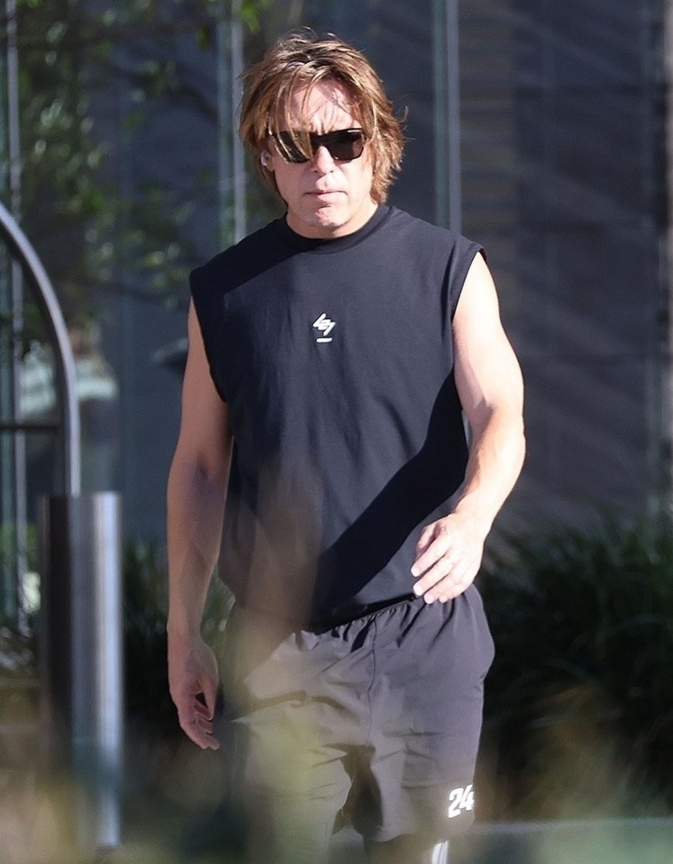 a man wearing sunglasses and a black sleeveless shirt has the number 24 on his shorts