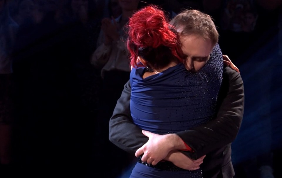 a woman with red hair is hugging a man in a suit