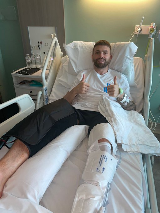 a man in a hospital bed giving a thumbs up