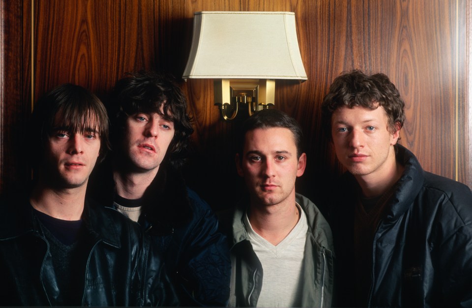 four men are posing for a picture in front of a lamp