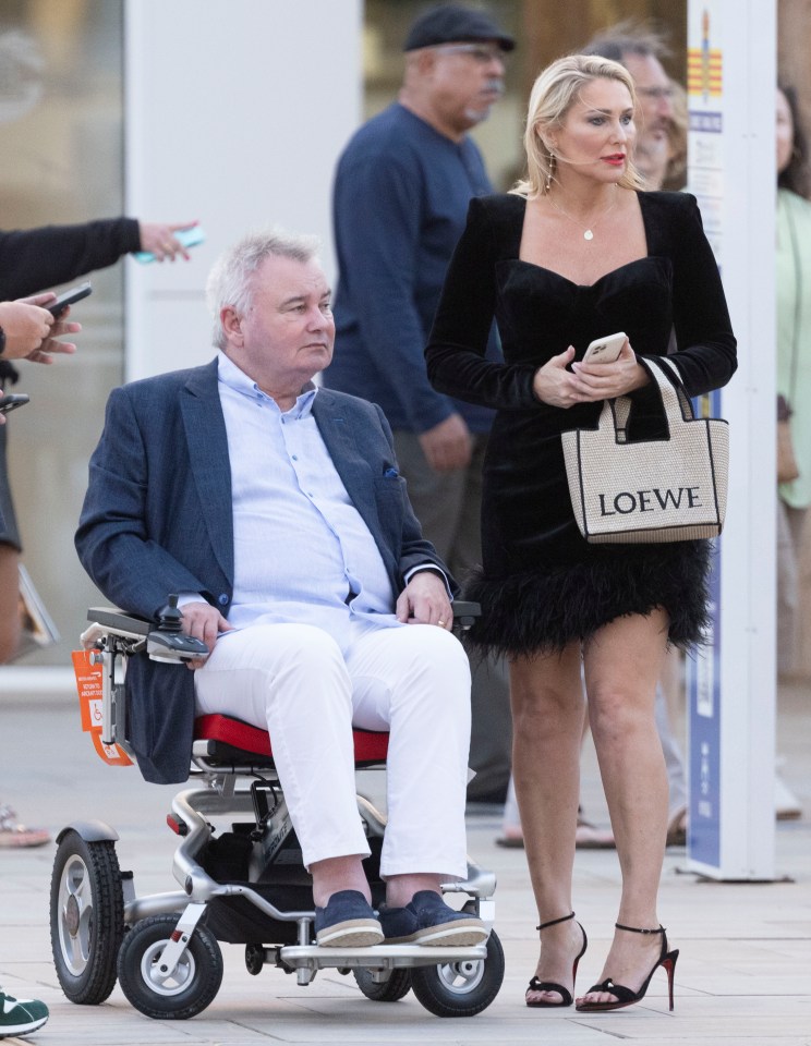 a man in a wheelchair next to a woman with a loewe bag